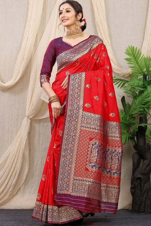 Elegant red Banarasi silk saree with intricate jacquard weaving, paired with a wine-colored unstitched blouse.